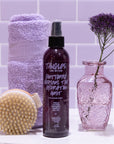 Bottle of 'Tangles and Beyond' product with a brush, towel, and vase on a tiled bathroom wall background.