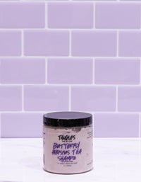 Jar of Tangles Butterfly Hibiscus Tea Shampoo against a purple tiled wall