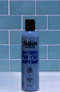 Bottle of 'Tangles and Beyond Butterfly Pea Tea Lush Toner' against a blue tiled wall.