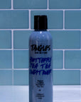 Bottle of 'Tangles and Beyond Butterfly Pea Tea Lush Toner' against a blue tiled wall.