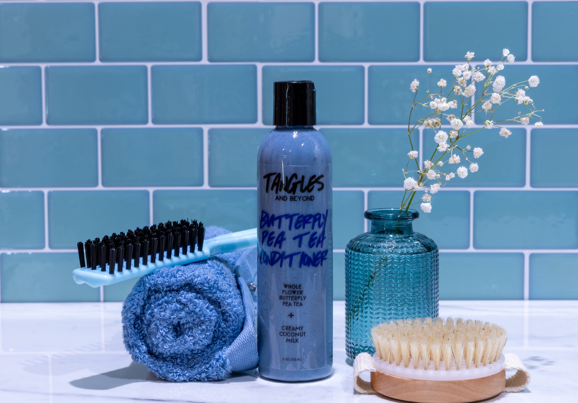 Bathroom setting with Tangles hair care products against a blue tiled wall.