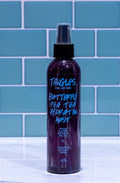 Bottle of 'Tangles and Beyond' hair product on a tiled surface with blue tiles in the background.