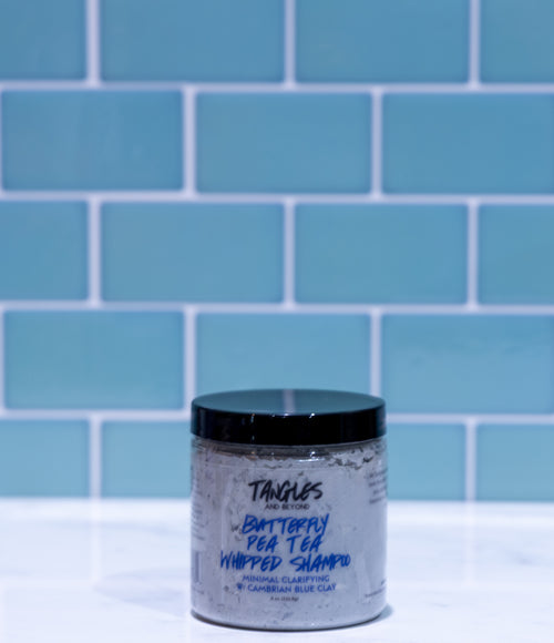Jar of shampoo with blue label against a blue tiled wall