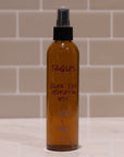 Bottle of Tangles Black Tea Hydration Mist on a tiled bathroom counter