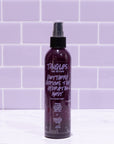 Purple spray bottle labeled 'Tangles and Beyond' on a white surface with purple tiled wall background