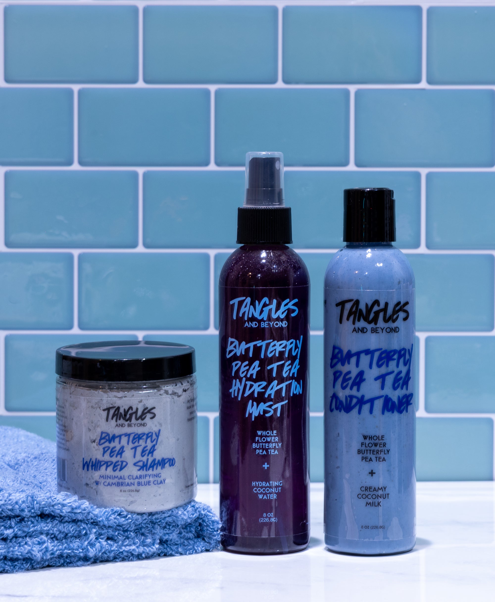 Three Tangles and Beyond haircare products against a blue tiled wall.