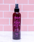 Bottle of Tangles & Beyond hair product with pink text on a pink tiled background