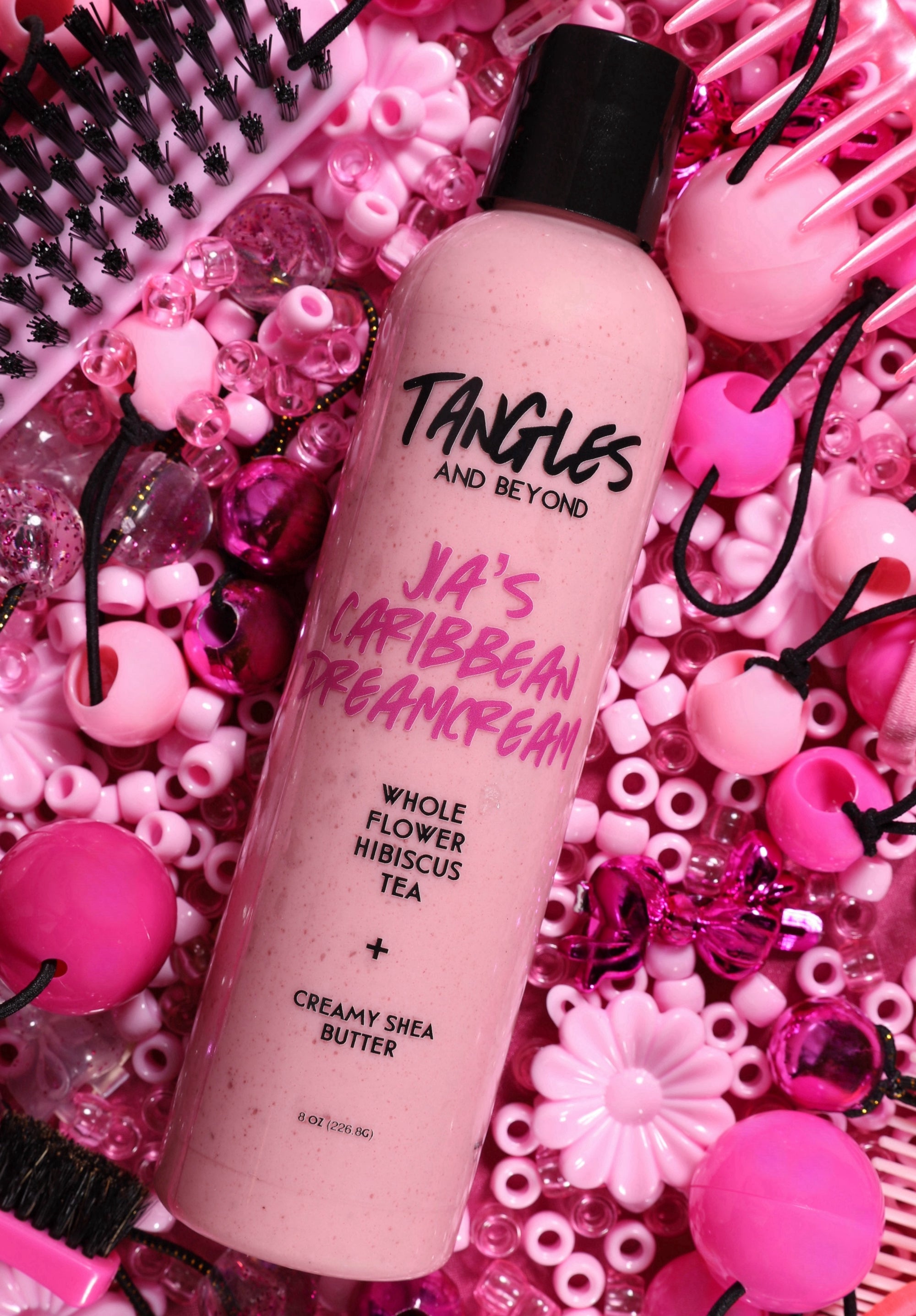 “DreamCream leave-in conditioner shea butter hibiscus curly hair detangler lying  on beads and barrettes."