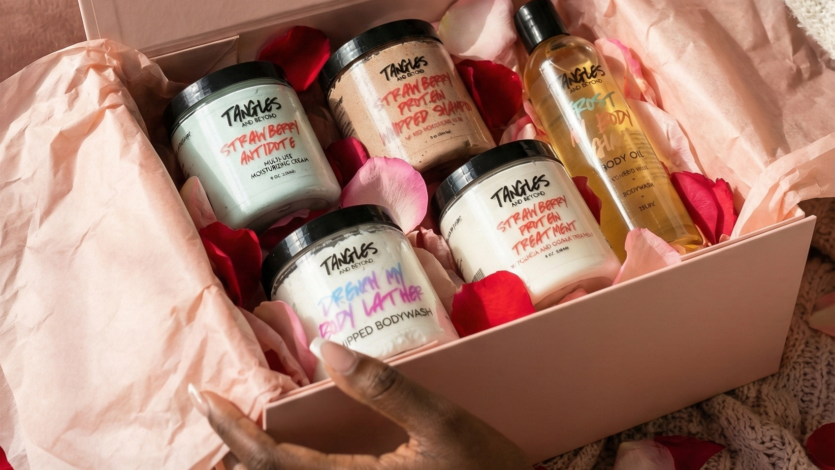 Person holding a box of Tangles and Beyond skincare products against a pink background
