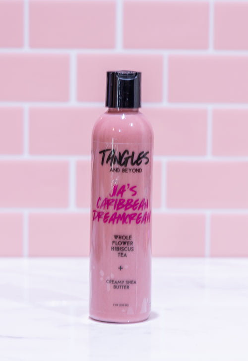 Pink bottle with black cap on a white surface against a pink tiled wall