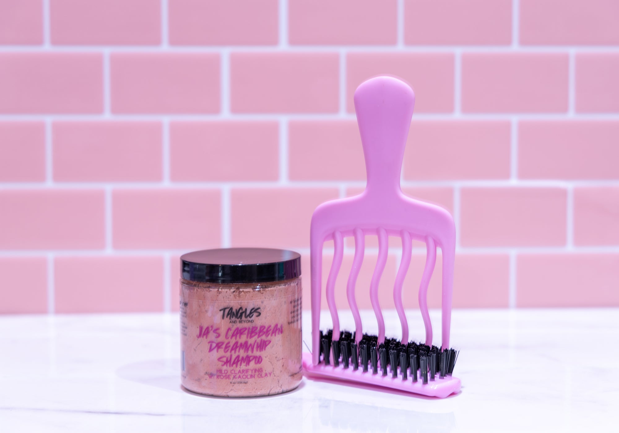 Pink comb and jar with text on a pink tiled wall background