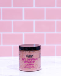 Jar of shampoo with visible branding against a pink tiled wall