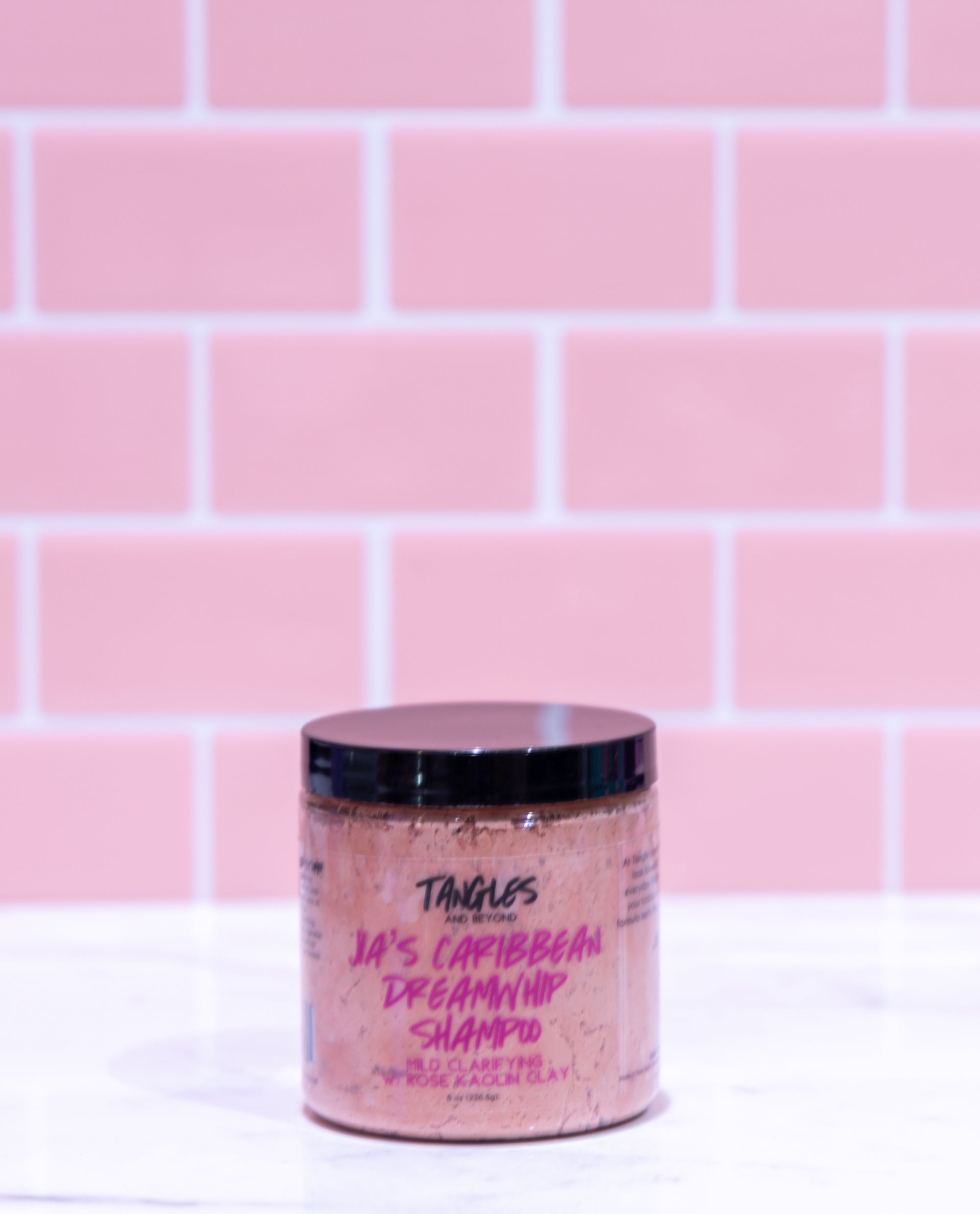 Jar of shampoo with visible branding against a pink tiled wall