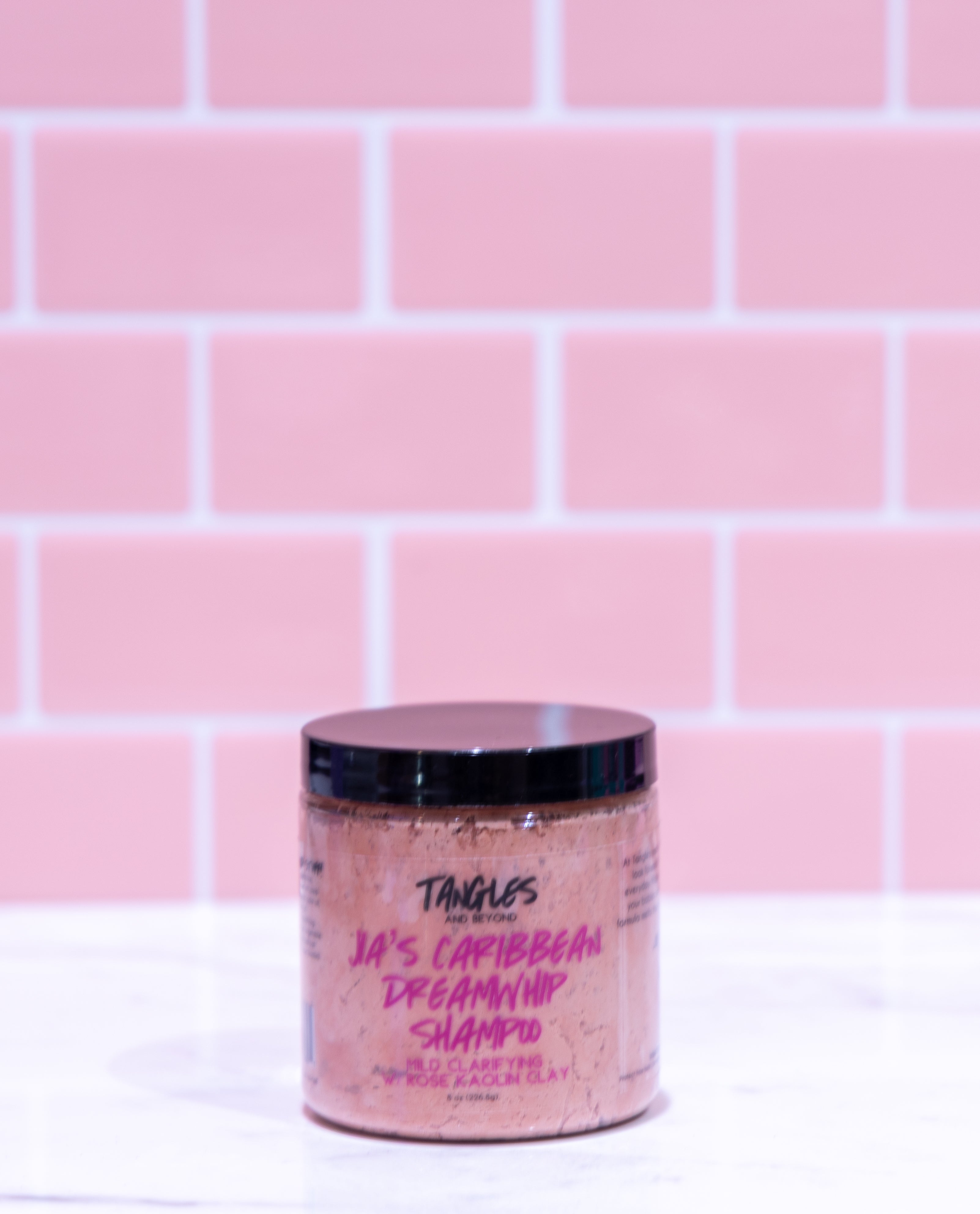 Jar of shampoo with visible branding against a pink tiled wall