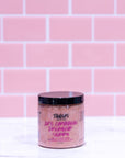 Jar of shampoo with visible branding against a pink tiled wall