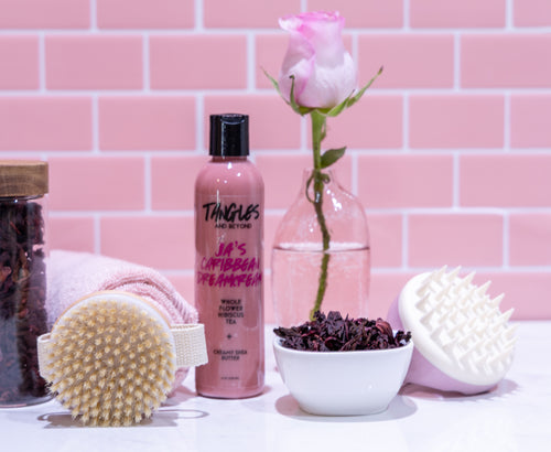Bottle of Tangles hair product with a pink rose, scrubber, and bowl on a pink tiled background