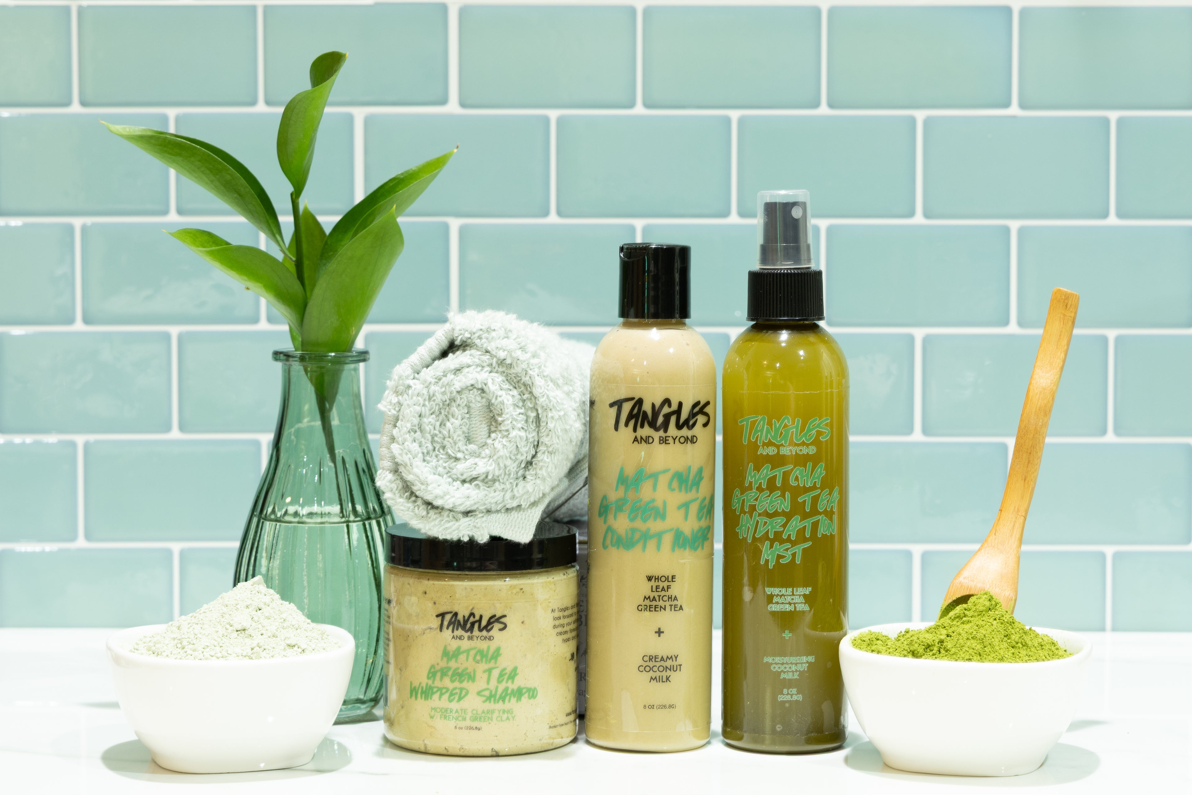Tanglos skincare products with a plant and towel against a tiled wall background