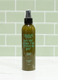 Green spray bottle with black nozzle on a light green tiled wall background