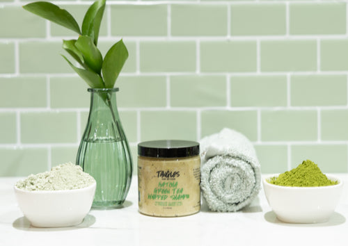 Matcha Green Tea Whipped Shampoo with greenery on a light green tiled wall background