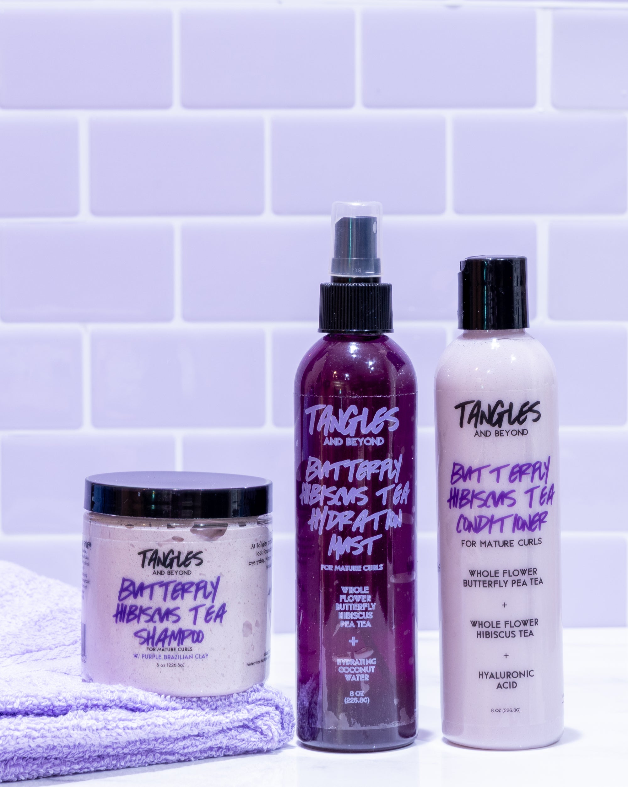 Tangles and Beyond hair care products on a purple tiled background