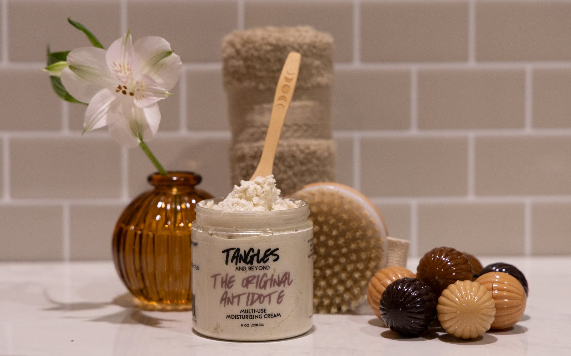 Cosmetic product with a wooden spoon and decorative items on a bathroom counter.