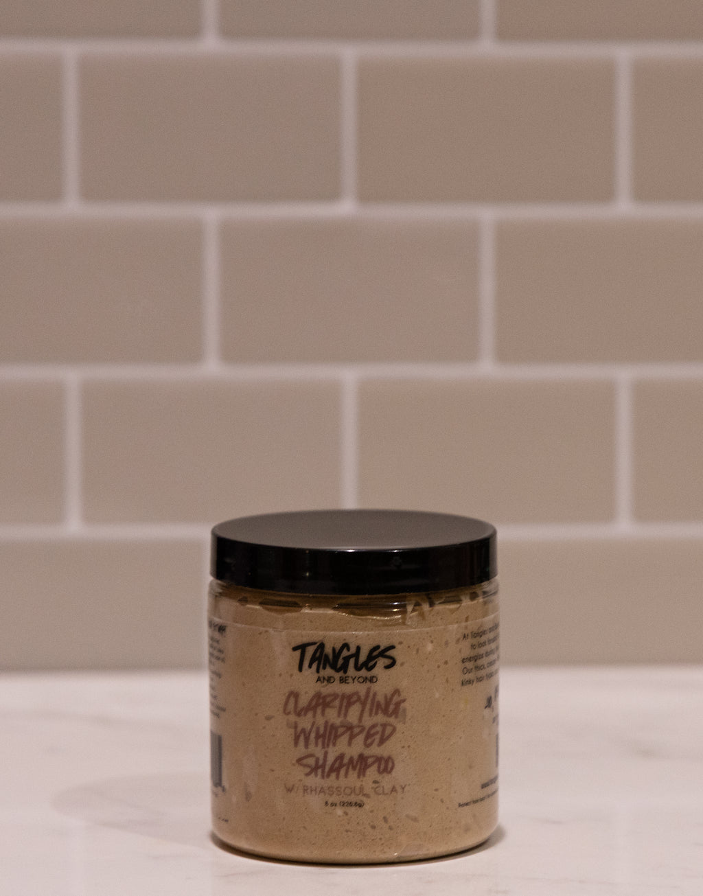 Jar of Tangles shampoo on a tiled bathroom floor