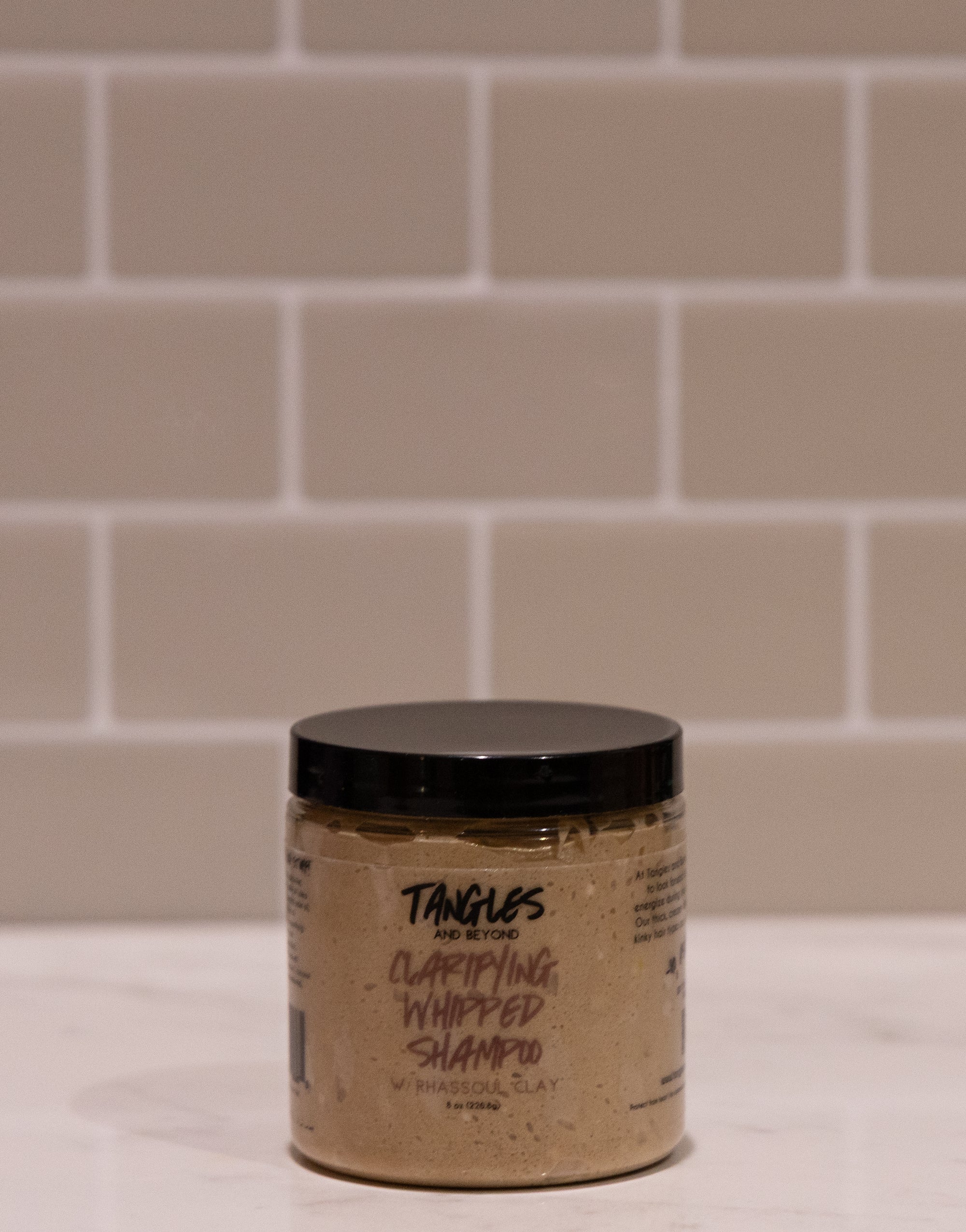 Jar of Tangles shampoo on a tiled bathroom floor
