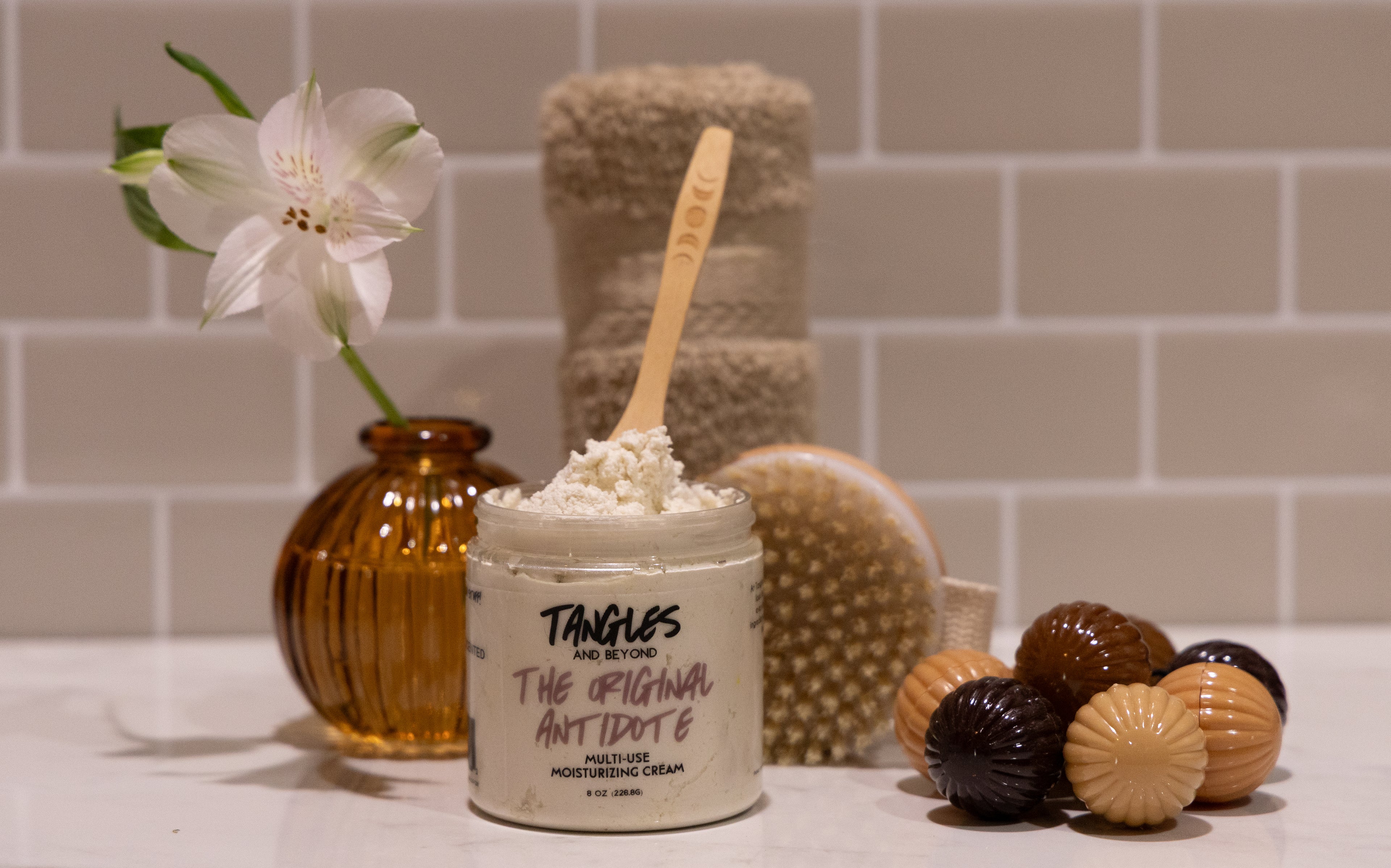 Cosmetic product with a wooden spoon and decorative items on a bathroom counter.